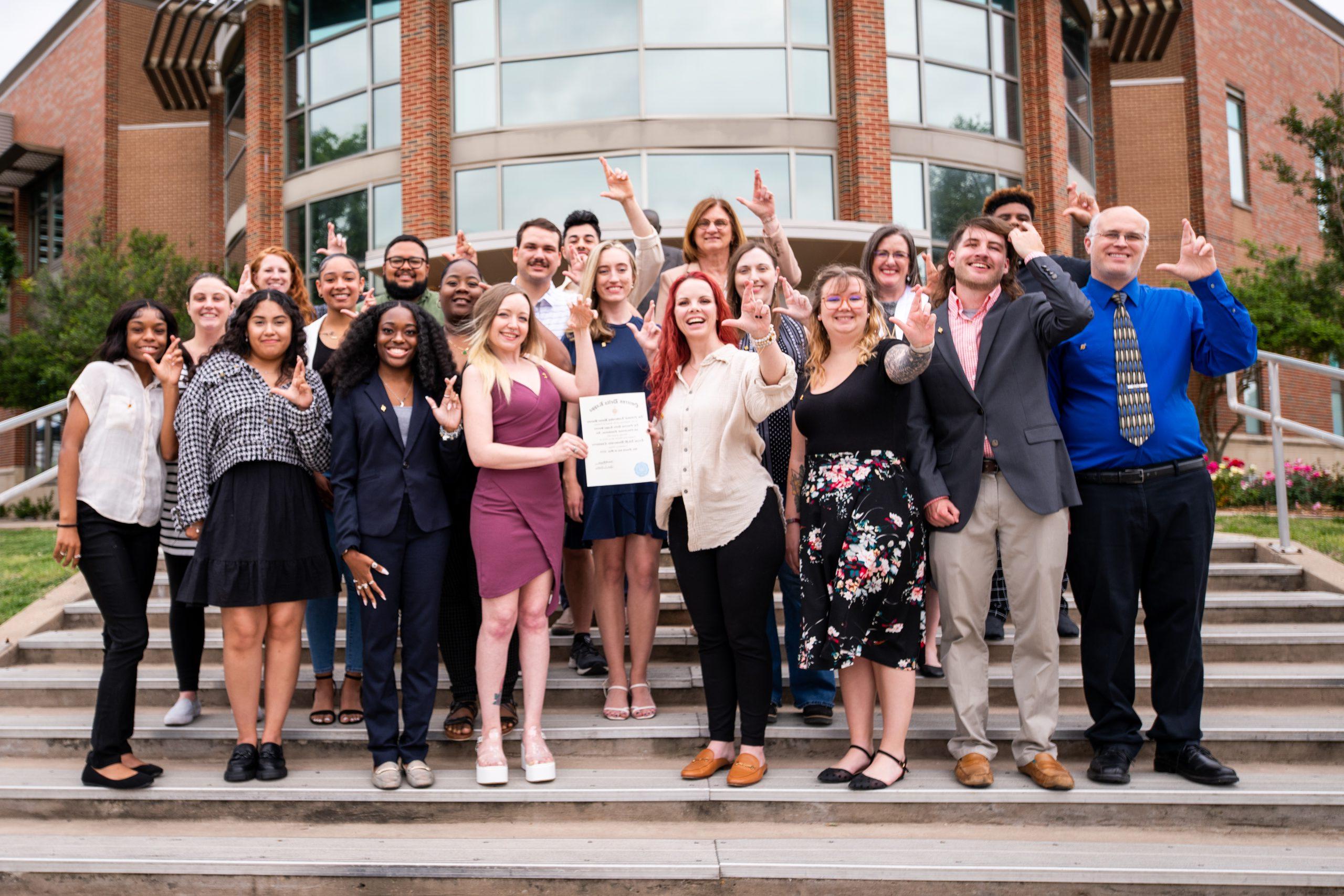 A group of females and males holding the Omicron Delta Kappa sign.